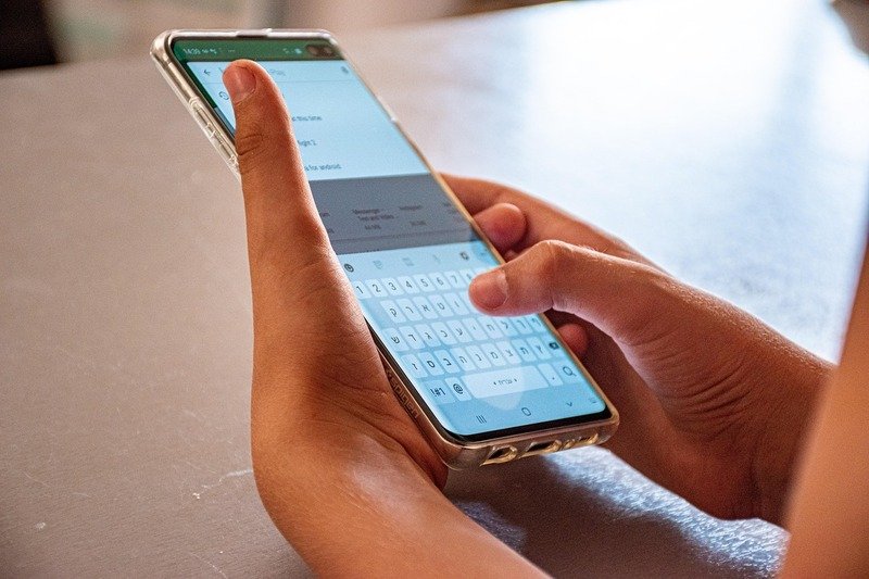 Manos escribiendo mensaje en celular con chat abierto de asesoría personalizada.
